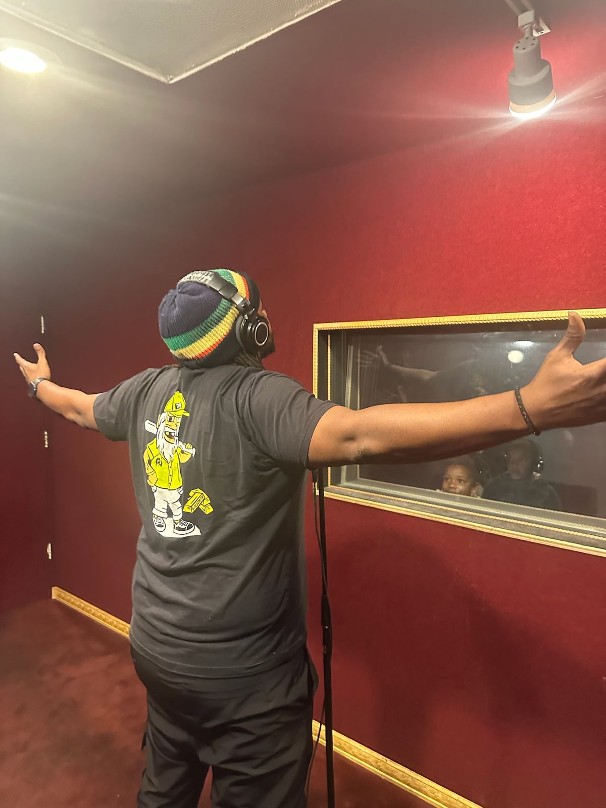 MT The Great with arms spread wide in the recording booth