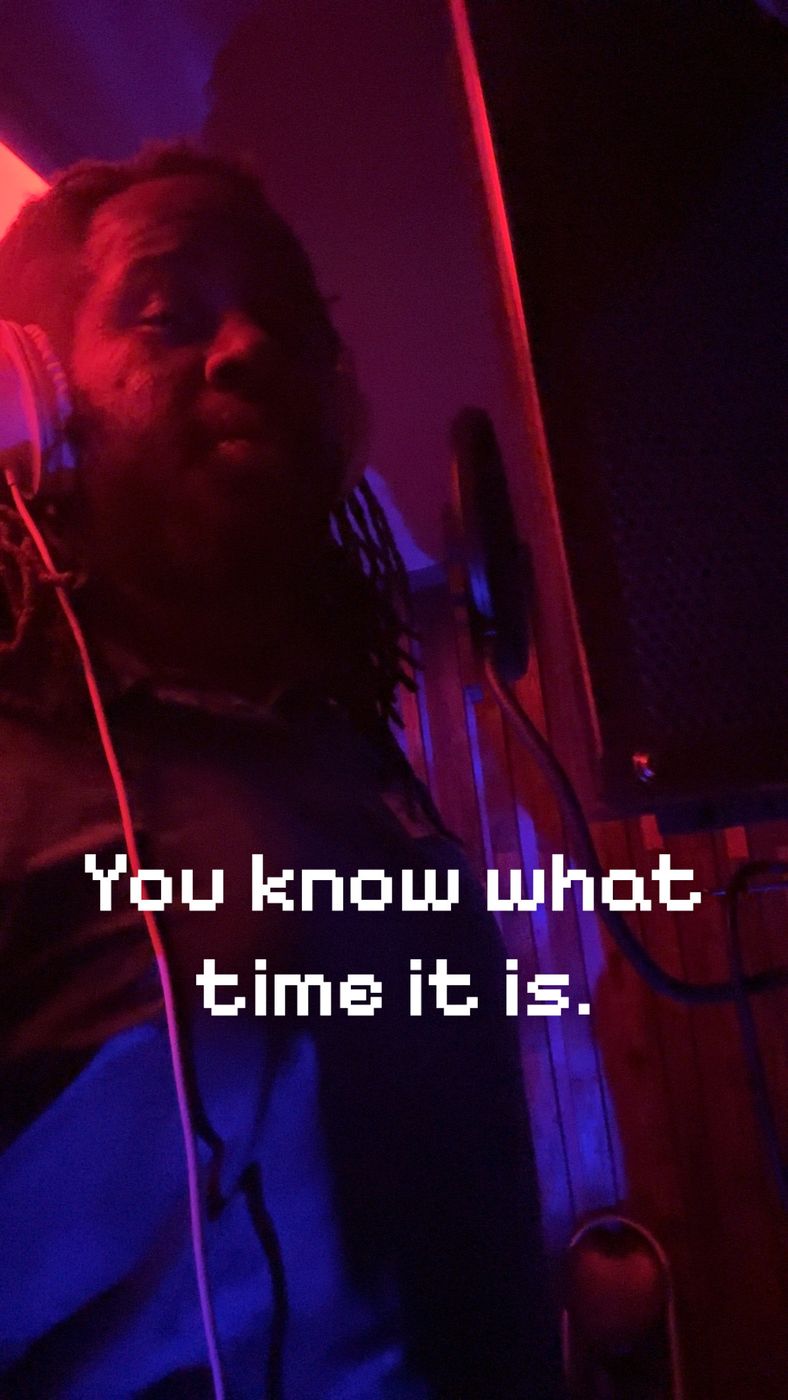 MT The Great on the mic under red and blue booth light, captioned You know what time it is